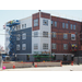 Workers continue to put the white and blue siding on the outside of the building and move on to the next side of the building